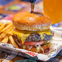 A cheeseburger with tomatoes and cheese, and fries on the side.